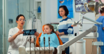 Pediatric woman dentist treating little girl patient in modern stomatological dentistry office showing teeth x-ray explaining to mother dental intervention. Visiting dentist with children.