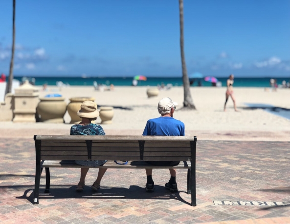 Retired couple sitting on a bench at the beach.