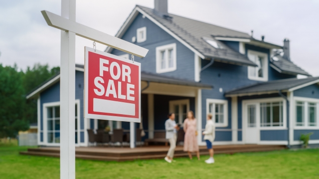 couple talking with realtor in front of house
