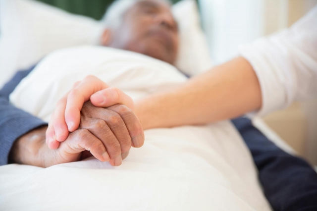 A nurse comforting a man in hospice care.