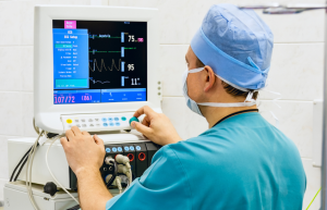 Medical professional operating a monitor interface.