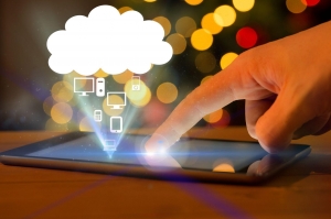  Hand touching a tablet that is displaying cloud communication among other devices 