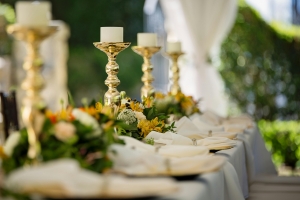 Elegant intimate wedding destination table setup with golden candle holders, white linens, and vibrant floral arrangements.