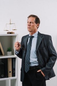 Portrait of contemplated mature lawyer with hand in his pocket