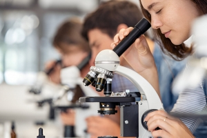 student seeing through microscope in science laboratory