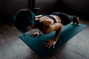 A woman works out, performing a plank. 