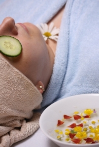 An image of a woman wearing a robe with cucumbers on her eyes 